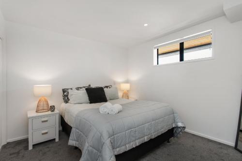 a white bedroom with a bed and a window at Affordable Apartment Hagley Park Super Fast Wifi in Christchurch