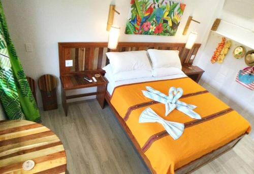 ein Schlafzimmer mit einem Bett mit orangefarbener Bettwäsche und Blumen darauf in der Unterkunft The Tiki Toucan Tropical Suite + Private Pool in Placencia Village