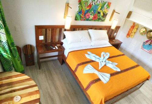 a bedroom with a bed with orange sheets and flowers on it at The Tiki Toucan Tropical Suite + Private Pool in Placencia Village