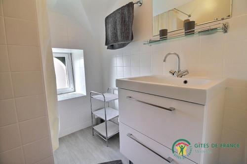 a white bathroom with a sink and a mirror at De la quenouille in Locoal-Mendon