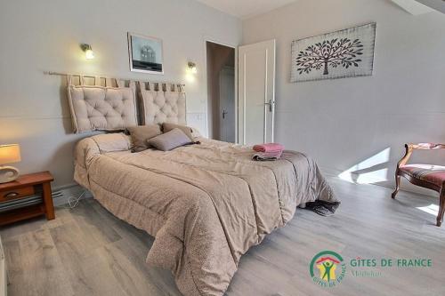 1 dormitorio con 1 cama grande y 1 silla en De la quenouille en Locoal-Mendon