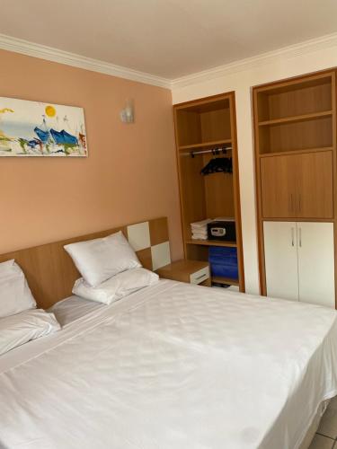 a bedroom with a large white bed and a cabinet at Diroma Fiori Hotel in Caldas Novas
