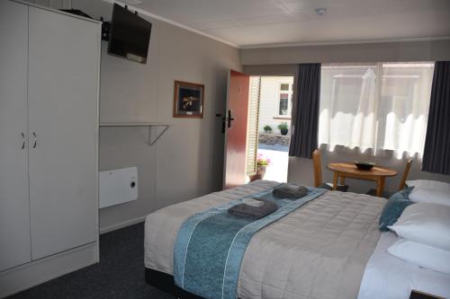 1 dormitorio con 1 cama, TV y mesa en Roxburgh Motels, en Roxburgh