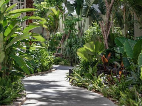 a walkway through a tropical garden with plants at Lotte Hotel Saigon in Ho Chi Minh City