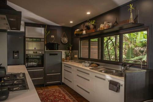 a kitchen with black walls and white cabinets and a sink at Dark Moon House in Yandina Creek