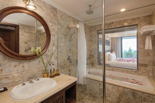 a bathroom with a sink and a shower and a mirror at Silk Path Grand Sapa Resort & Spa in Sa Pa
