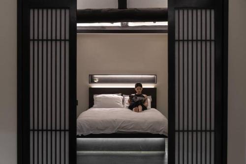a young boy sitting on a bed reading a book at Yeojuhyeon in Daegu