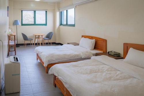 Habitación de hotel con 2 camas, mesa y sillas en 06聚點 06 Gather Point, en Beigan