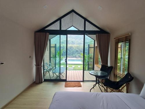 a bedroom with a bed and a view of a patio at Lake Hill Resort Kanchanaburi in Tha Kradan