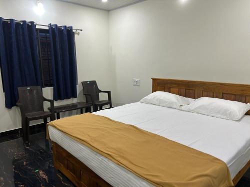 a bedroom with a large bed and two chairs at Yashovana Nature Stay Gokarna in Gokarna