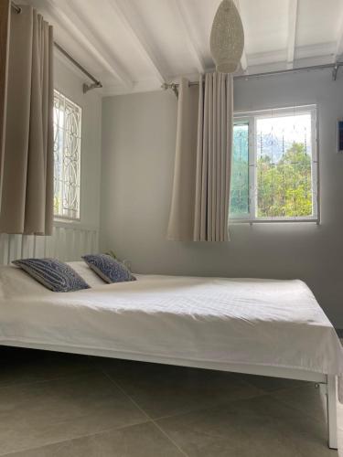 - un grand lit dans une chambre avec 2 fenêtres dans l'établissement ชมธารา วิลล่า, à Ranong