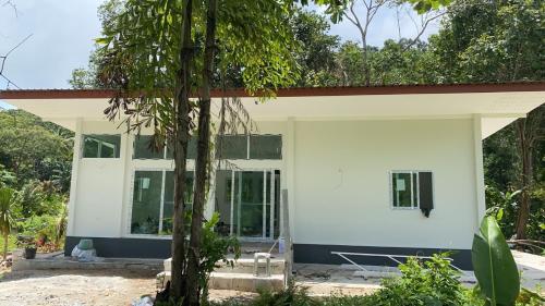 une maison blanche avec un toit rouge dans l'établissement ชมธารา วิลล่า, à Ranong