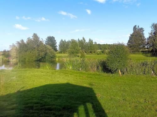 uma sombra de uma pessoa na relva ao lado de um lago em Buzzard - Uk41951 em Louth