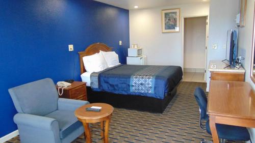 a hotel room with a bed and a chair at Corcoran Country Inn in Corcoran