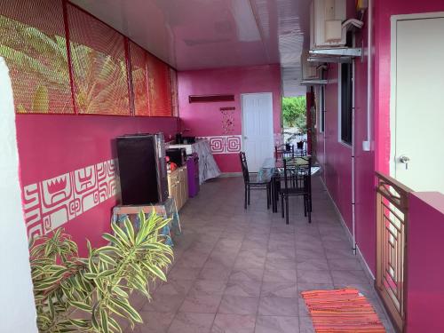 a room with a purple wall with a table and chairs at CHEZ ALIZHIA in Nuku Hiva