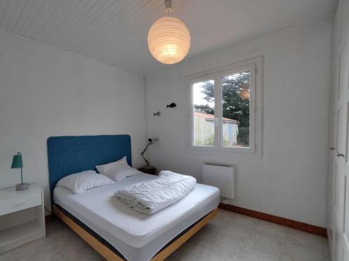 - une chambre avec un lit doté d'une tête de lit bleue et d'une fenêtre dans l'établissement Grande Maison Familiale à 300m Plage, Jardin, et Véranda - Saint-Georges-d'Oléron - FR-1-778-15, à Saint-Georges-dʼOléron