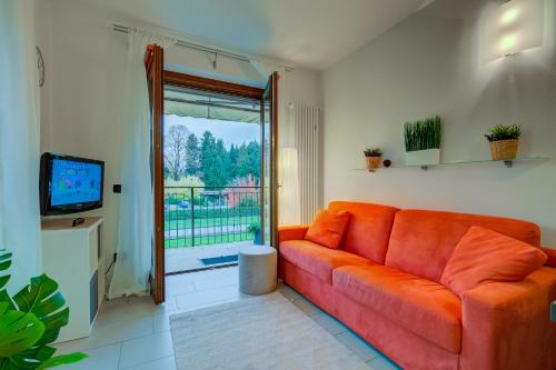 un sofá naranja en la sala de estar con TV en Lenni Apart Swimming Pool and lake - Happy Rentals, en Leggiuno