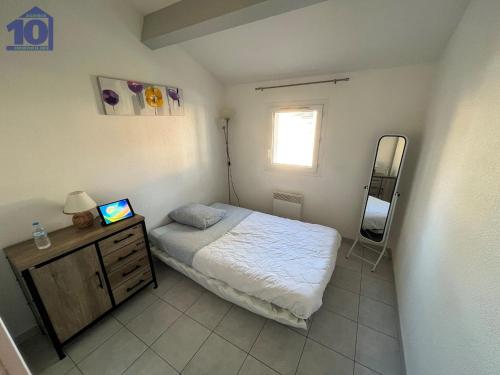 ein kleines Schlafzimmer mit einem Bett und einem Spiegel in der Unterkunft Maison Valras-Plage, 3 pièces, 5 personnes - FR-1-781-15 in Cité de la Raye Dieu
