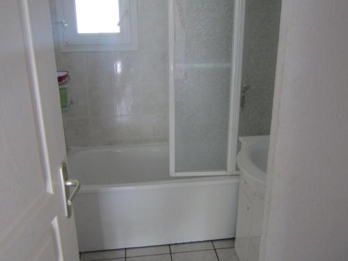een witte badkamer met een bad en een wastafel bij Maison Valras-Plage, 2 pièces, 6 personnes - FR-1-781-18 in Valras-Plage