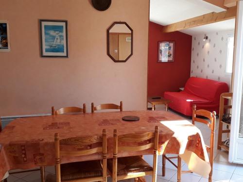 a living room with a wooden table and a red couch at **Maison récente, proche plage, commerces et plan d'eau - L'Aiguillon-sur-Mer** - FR-1-194-275 in LʼAiguillon-sur-Mer