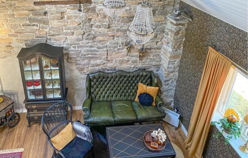 a green leather couch in a room with a stone wall at 3 Bedroom Stunning Home In Degerhamn in Degerhamn