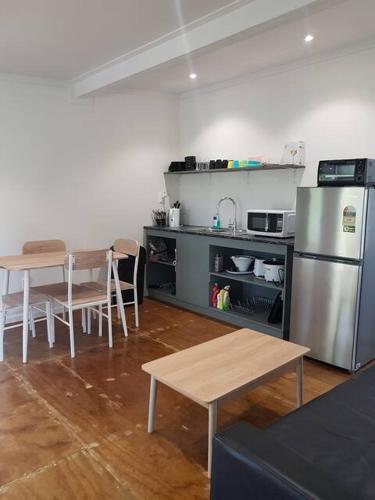 a kitchen with a table and a stainless steel refrigerator at Kaina Kaute in Alofi