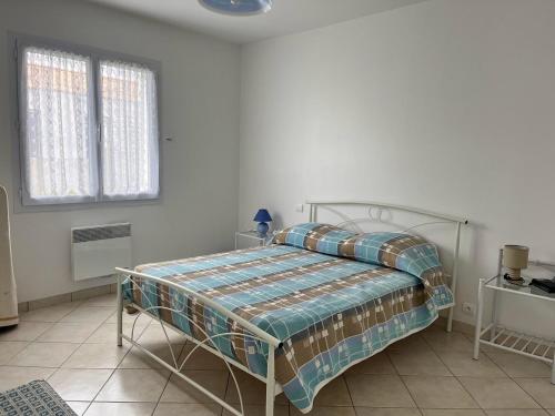 ein Schlafzimmer mit einem Bett in einem weißen Zimmer in der Unterkunft Maison L'Aiguillon-sur-Mer, 3 pièces, 6 personnes - FR-1-194-277 in LʼAiguillon-sur-Mer