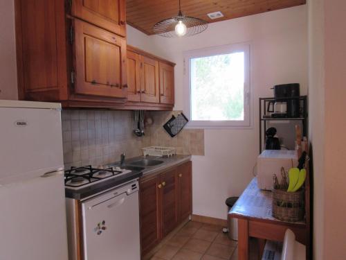 une cuisine avec des armoires en bois et un réfrigérateur blanc dans l'établissement Maison avec jardin clos, près de la mer et de la forêt, équipée pour famille et animaux admis - FR-1-194-281, à La Faute-sur-Mer