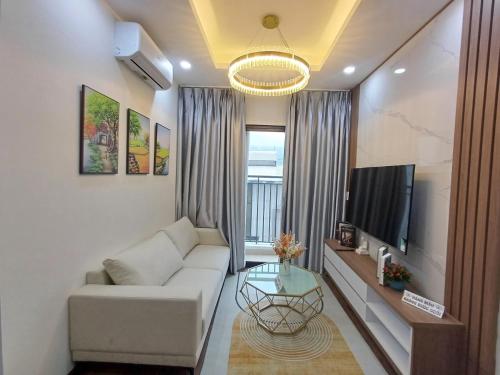 a living room with a white couch and a tv at Mami House - Luxcity Cẩm Phả Serviced Apartments in Cẩm Phả