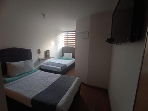 Habitación pequeña con 2 camas y TV. en ARENA PARK, en Bogotá