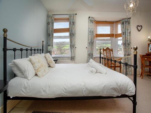 1 dormitorio con 1 cama con sábanas y almohadas blancas en Hill View en Sidmouth