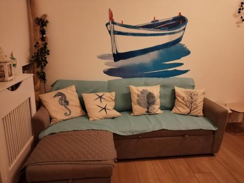 a couch with pillows and a painting of a boat at Triremi house in Lido di Ostia