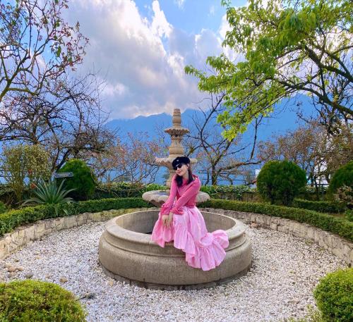 a woman in a pink dress sitting on a fountain at Silk Path Grand Sapa Resort & Spa in Sa Pa
