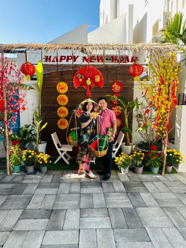 a man and woman standing in front of a happy new year sign at Muine Sports Hotel in Mui Ne