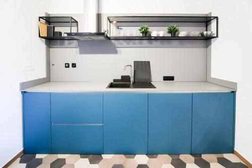 a kitchen with blue cabinets and a sink at Apartmani Jana in Osijek