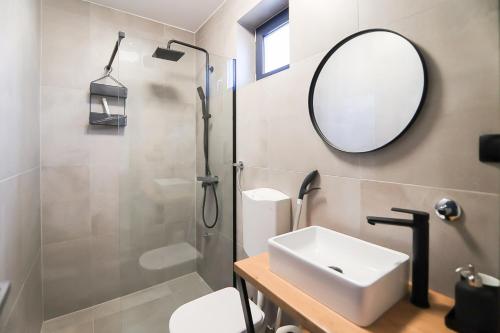uma casa de banho com um lavatório, um espelho e um chuveiro em Apartmani Jana em Osijek