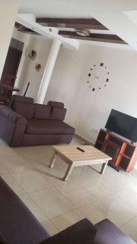 ein Wohnzimmer mit einem Sofa, einem Tisch und einer Uhr in der Unterkunft Cozy Homes Shared 1 in Kigali