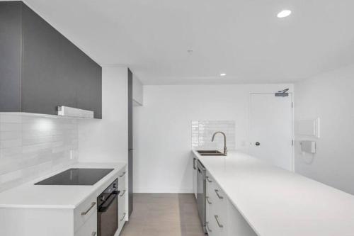 a white kitchen with a sink and a counter at Loft Rockhampton in Rockhampton