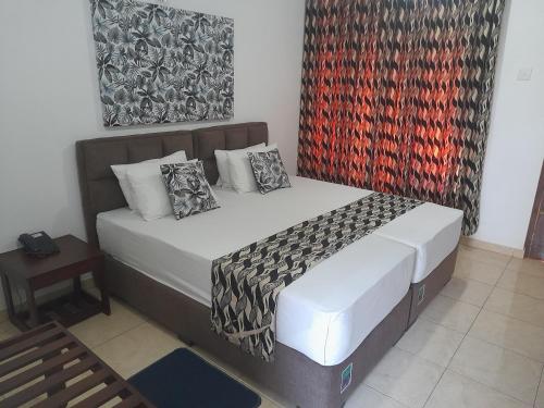 a bedroom with a bed and a painting on the wall at Larn's Villa Hotel & Apartment in Wadduwa