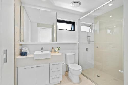 a white bathroom with a toilet and a shower at Spice Broadbeach - GCLR in Gold Coast