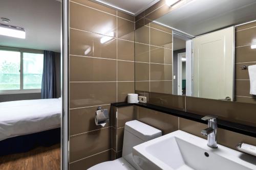 a bathroom with a toilet and a sink and a mirror at Kensington Resort Jeju Hanlim in Jeju