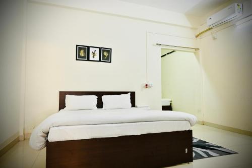 um quarto com uma cama grande e lençóis brancos em Queen's Residency em Guwahati