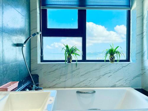 a bathroom with a window with two potted plants at ALTARA Quy Nhơn - RUBY Luxury Apartment in Quy Nhon