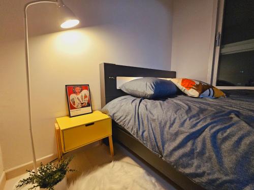 a bedroom with a bed and a night stand with a picture at 서울의 야경이 멋진 옐로우 하우스 in Seoul