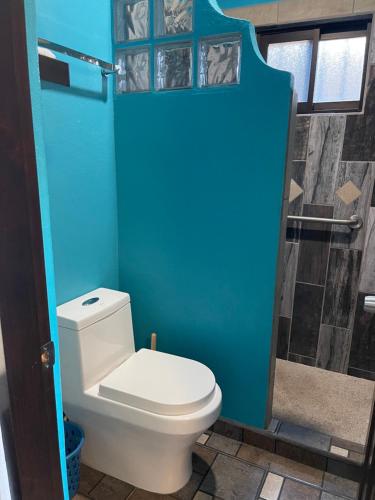 a bathroom with a white toilet and a blue wall at Suitecasita #1 in Loreto