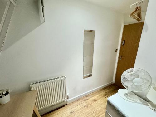 um quarto com uma parede branca e uma ventoinha em Kamilla's Rooms London Zone-1 em Londres