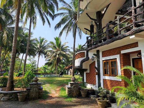 a house with palm trees in front of it at The Nature Park Villa in Sigiriya