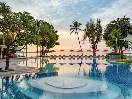 a swimming pool at a resort with trees and umbrellas at Amari Koh Samui in Chaweng