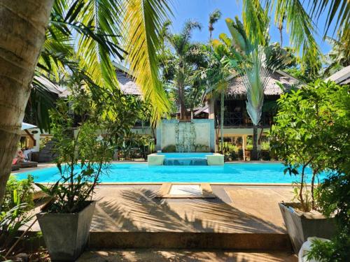 a resort swimming pool with a fountain and palm trees at Garden Chalets Koh Lanta in Ko Lanta