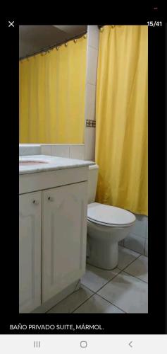 a bathroom with a toilet and a yellow shower curtain at Habitaciones en las condes, Cercano a metro in Santiago